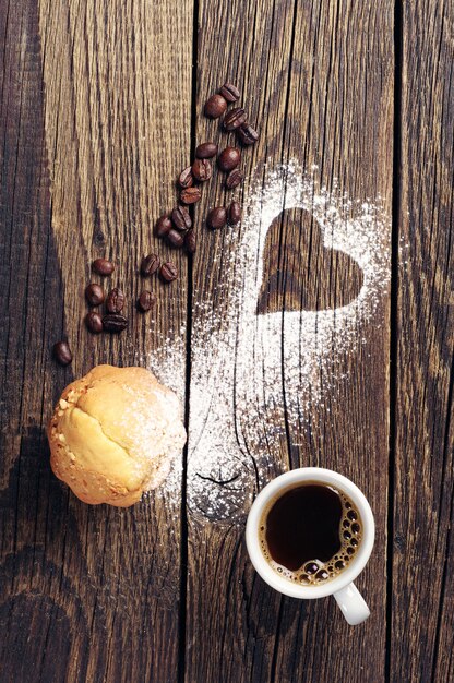 Muffin and cup of coffee on vintage wooden background with heart