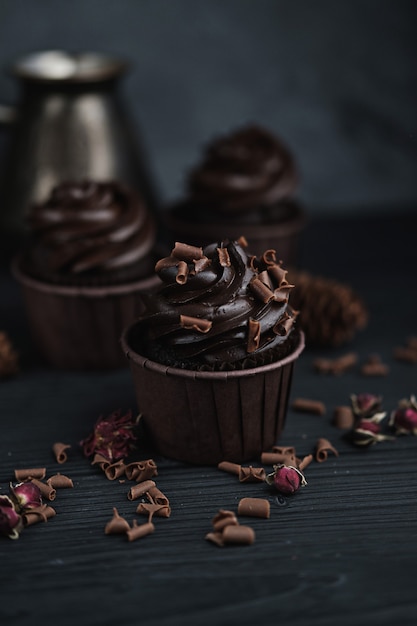 Photo muffin or cupcake with chocolate shaped cream at black table. flatlay top view.