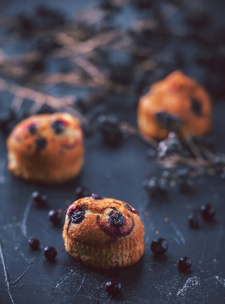 Muffin met aalbessen op een donkere achtergrond naast de bessen op de takken. in rustieke stijl. donkere stijl