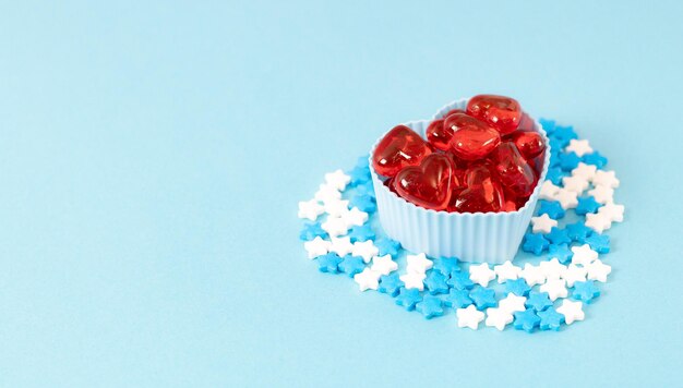 Muffin molds with red hearts and candy sprinkles on blue