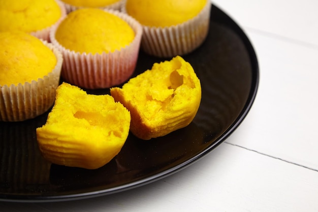 Muffins on black plate on white wooden table halved pumpkin cupcake homemade bakery flour product