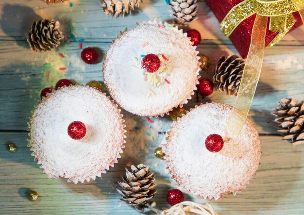 Muffins, cakes with cranberry and pecan nuts. On the background of cones and present. Christmas time