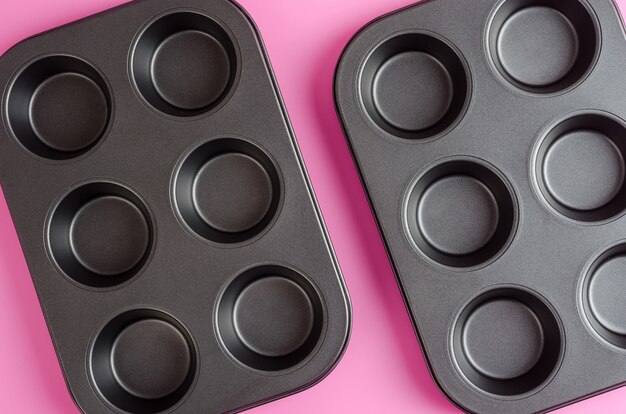 Muffins and cupcakes baking tin on a pink background.