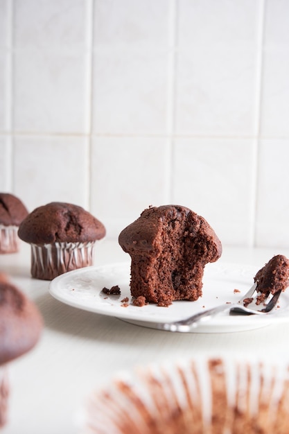 Muffins eten met een vork Muffins in papieren bekers op een bord Ontbijttijd Witte keuken achtergrond.