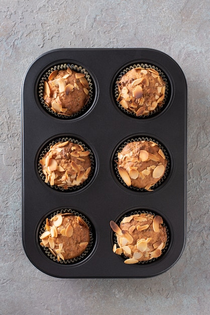 Muffins met kwark versierd met amandelschilfers in een ovenschaal.