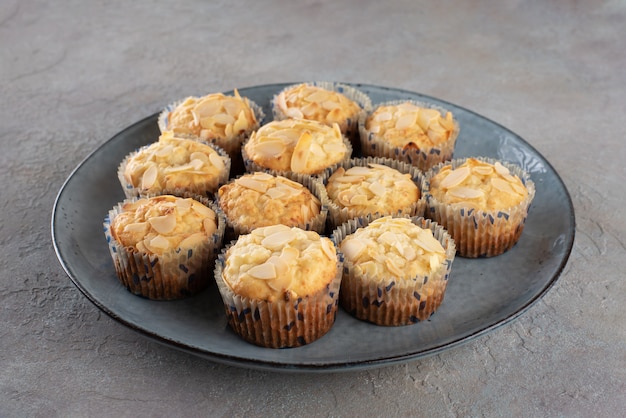 Muffins with cottage cheese decorated with almond flakes on a blue plate.