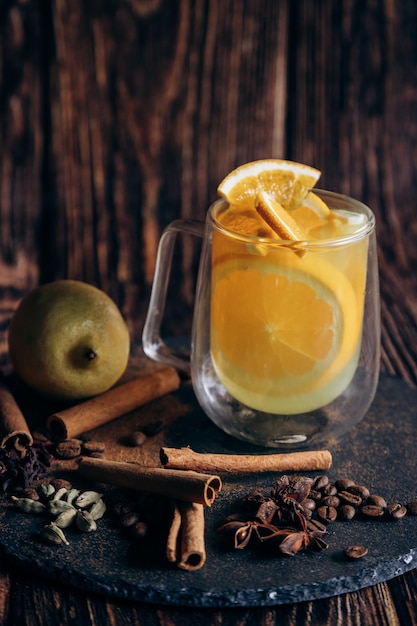 A mug of apple cider with a slice of lemon and cinnamon on the side.