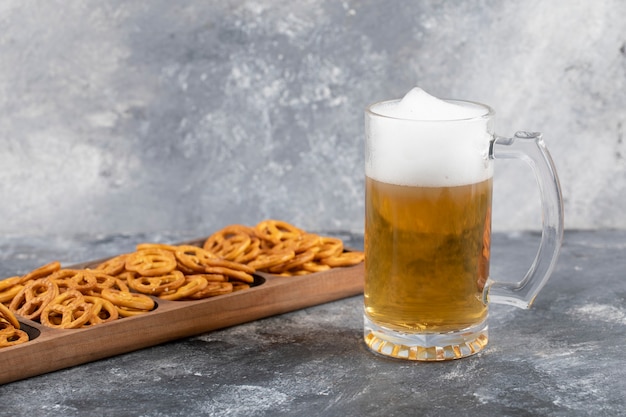 Mug of beer and snacks on stone surface.