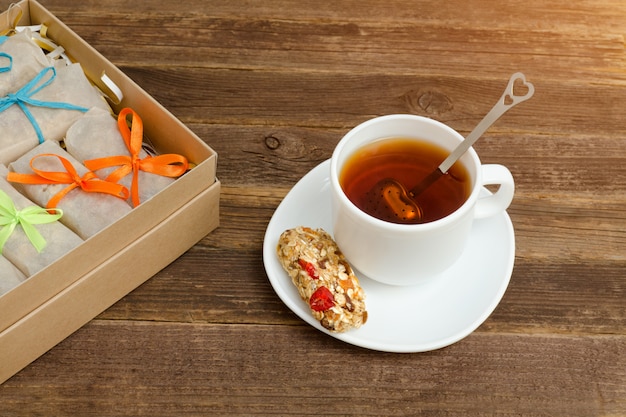 Mug of black tea, a bar of muesli and boxes with bars