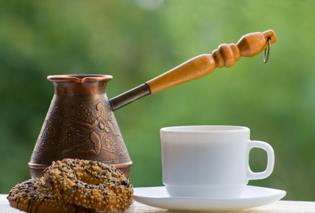 Mug coffee, cookies and copper pots outdoors on green wall