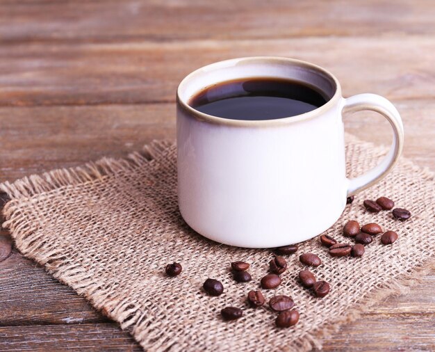 Mug of coffee on sackcloth on wooden background