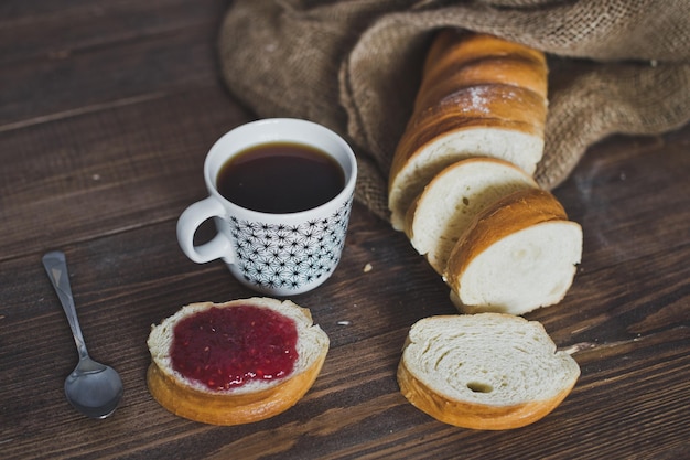 Mug of coffee and a sandwich from the loaf with jam 5086