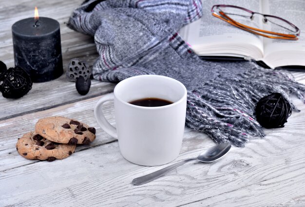 Mug of coffee withscarf and candle  on a white table