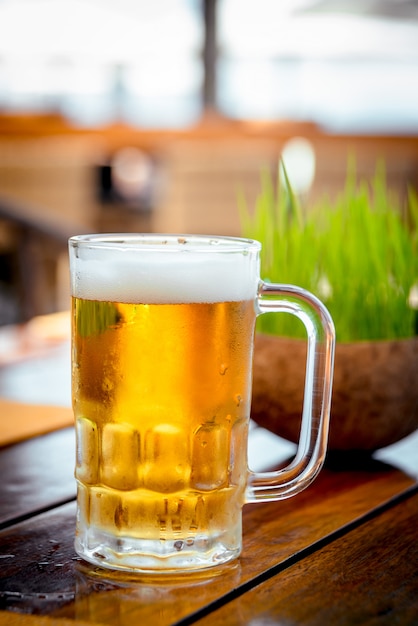 Mug of cold beer with foam on the table.