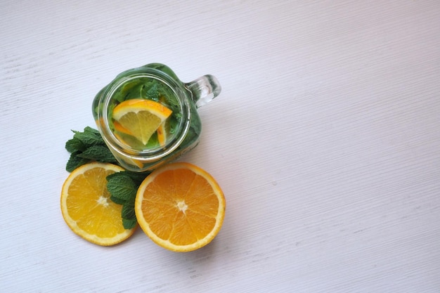 Mug of detox water with oranges and mint View from above