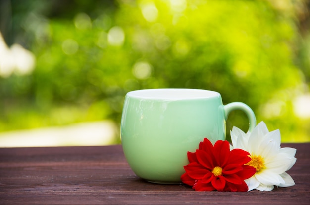 Tazza e fiori su sfondo sfocato verde