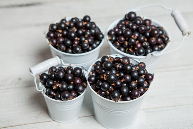 Mug of fresh ripe sweet blackcurrants on wooden surface