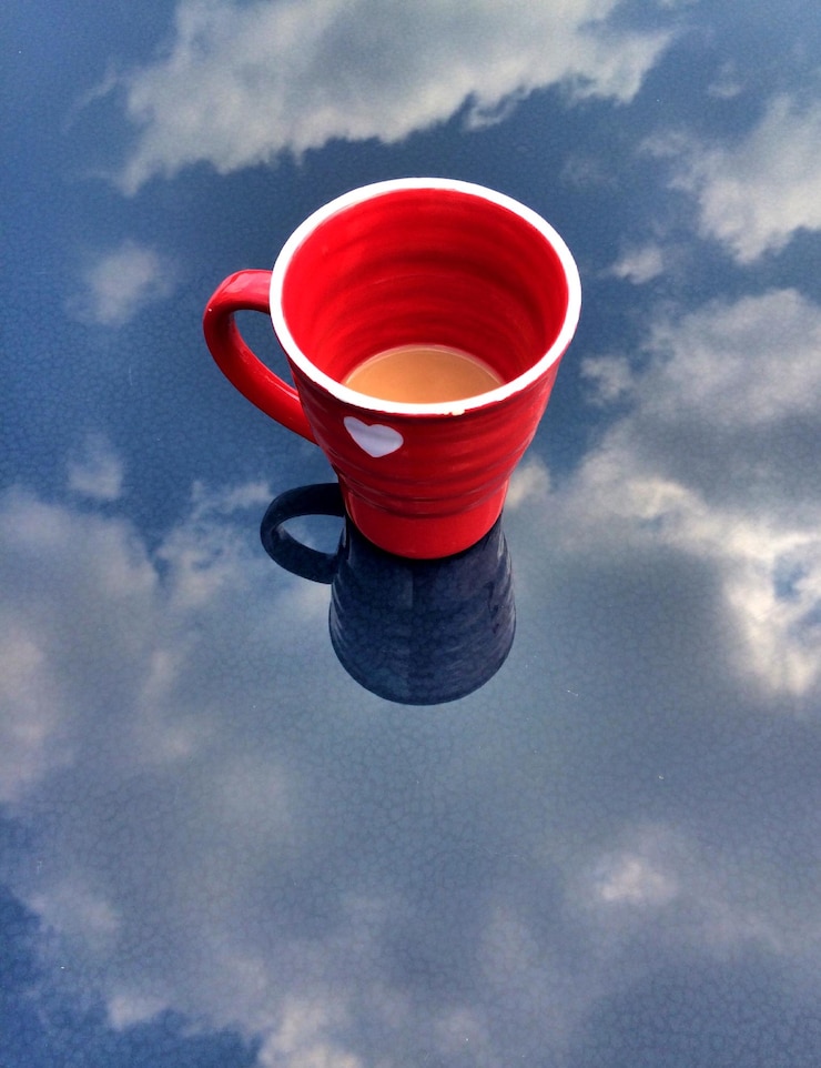 फोटो mug on glass surface with sky reflection