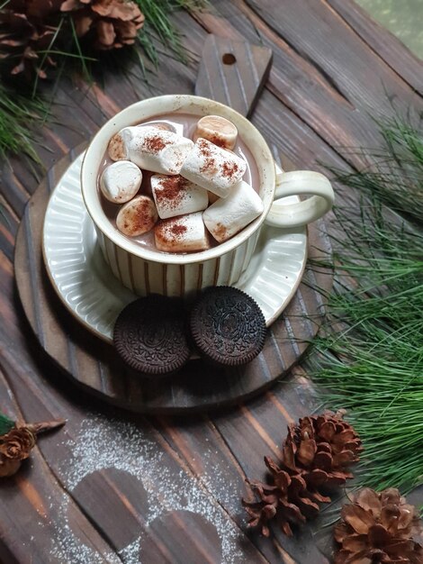 Кружка горячего шоколада с зефиром и орео на деревянном столе.