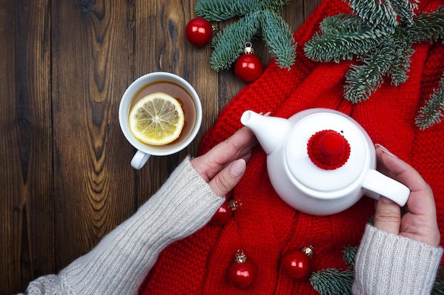 A mug of hot tea with lemon is in women's hands