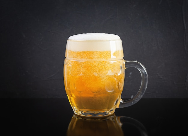 Mug of light beer on dark background. Craft unfiltered beer