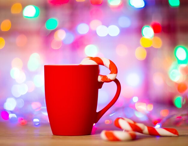 お茶やコーヒーのマグカップ。お菓子。クリスマスの飾り。赤いボールとベル。木製の背景。