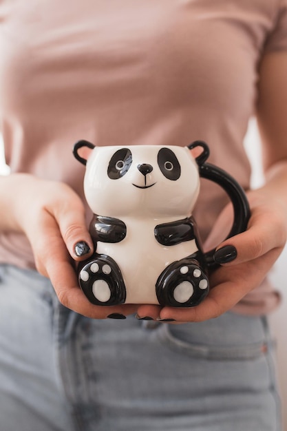 Tazza a forma di panda per caffè e tè nelle mani di una ragazza