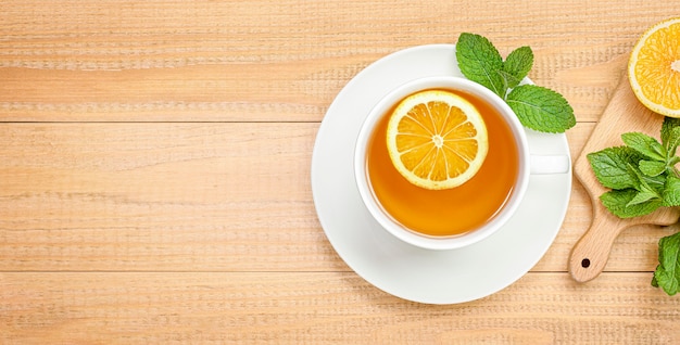 Mug of tea with mint and lemon on a wooden background. view from above