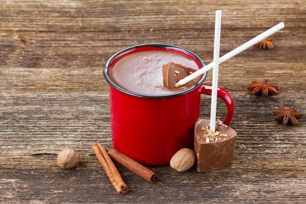 Tazza con cioccolata calda e spezie su tavola di legno