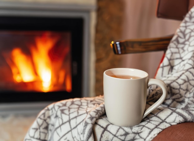 写真 暖炉のある居心地の良いリビングルームでウール製の毛布を被った椅子の上に立っている熱いお茶のカップ ai生成