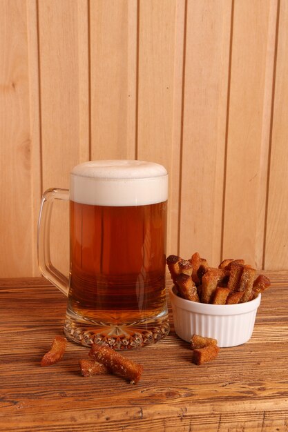 写真 木製のテーブルに軽いビールと塩味のクラッカーとマグカップ