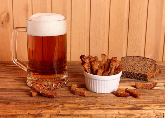 Foto tazza con birra leggera e cracker salati su un tavolo di legno