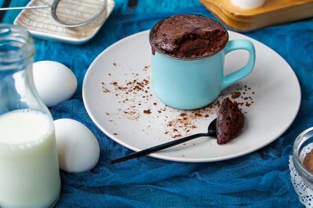 Il mugcake viene cotto al microonde il cupcake fatto in casa in una tazza è su un piatto torta in tazza con brownie al cioccolato