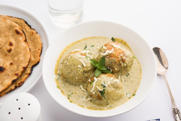 Mughlai 또는 Haryanvi 스타일의 Methi Malai Kofta 흰색 크림, 인기 있는 인도 채식 메인 코스는 Chapati 또는 Roti가 포함된 나무 그릇에 제공되며 선별적인 초점을 맞춥니다.