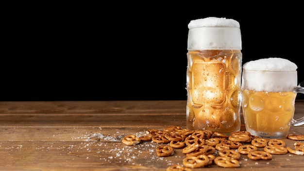 Mugs of beer with pretzels on a table