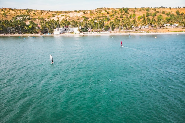 Mui Ne, Vietnam. Man speelt windsurfsport in de zee onder de uitgestrekte blauwe hemel.