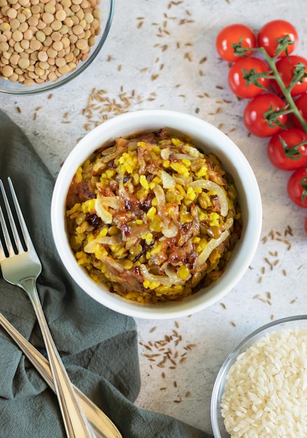 Mujadara lentils and rice pilaf with fried onions on light background vertical