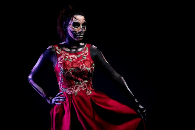 Mujer con Body paint de calavera met vestido Rojo en fondo azul por dia de muertos