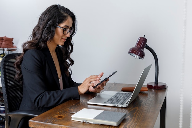 Mujer de negocios trabajando en casa y enviando mensajes con su celular