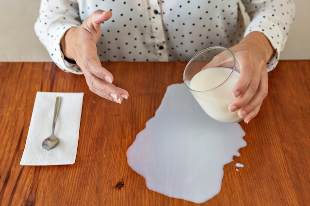 Женщина деррама un vaso de leche en la mesa