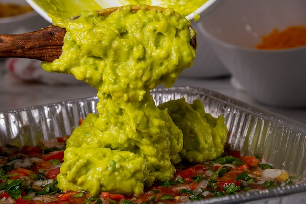 Mujer joven sirviendo aguacate en un plato de ensalada picada en un plato grande