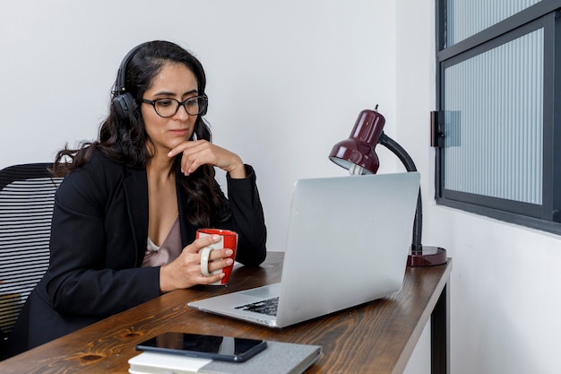 Mujer latina discutiendo en video conferencia trabajando en casa