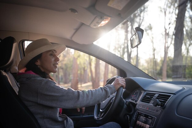 Mujer latina met sombrero conduciendo auto en reserva natural