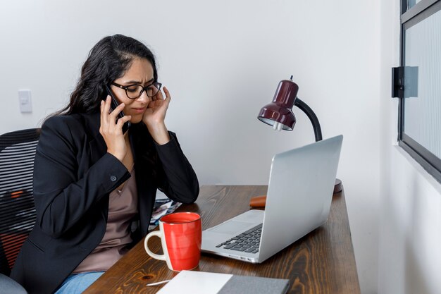 Mujer molsta hablando por telefono mientras trabaja desde cas debido a la pandemia