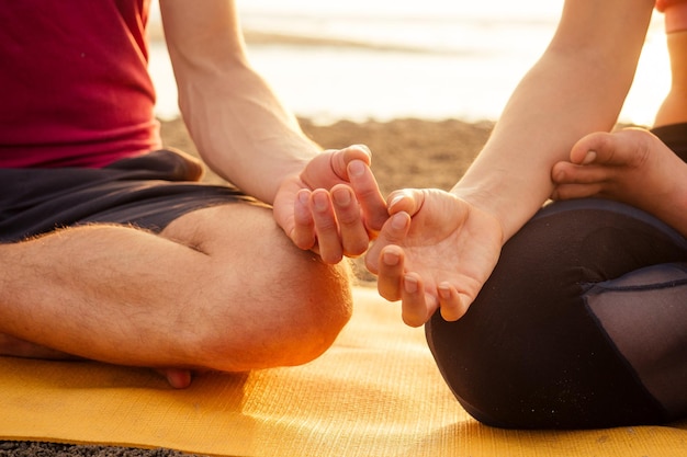 Муладхара свадхистана манипуля тантра йога на пляже мужчина и женщина медитируют, сидя на песке у моря на закате романтический День святого Валентина. Пара практикующих паровую йогу.