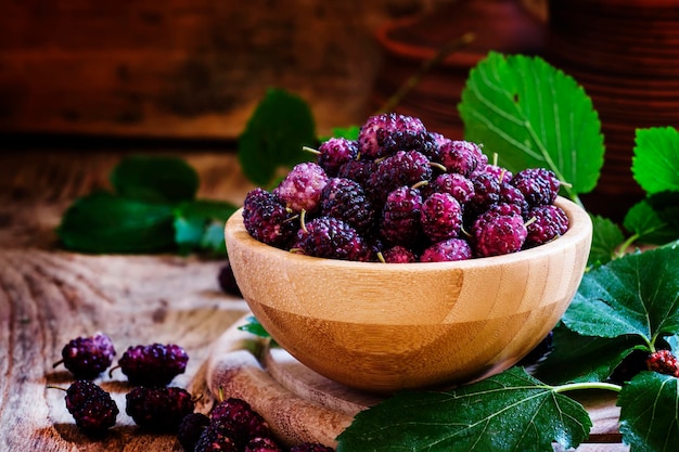 Mulberry in bowl with leaves vintage wooden background selective focus