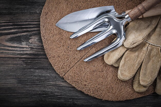 Mulching fiber hand spade troffel vork lederen beschermende handschoenen op houten plank tuinieren concept.