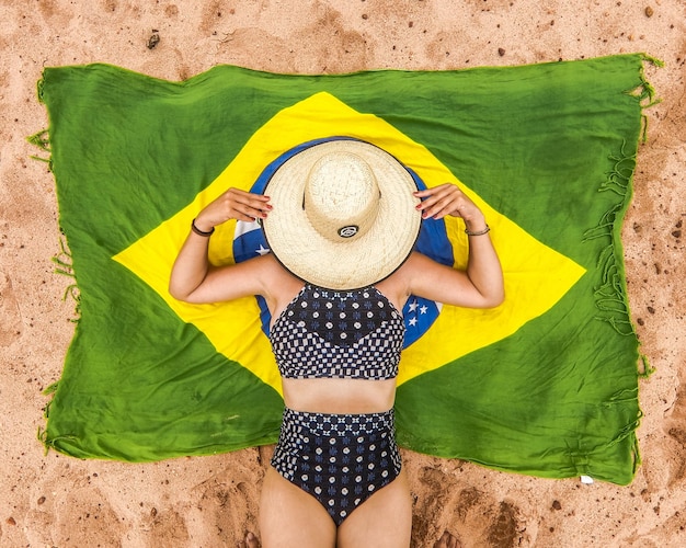 Foto mulher deitada sobre bandeira do brasil