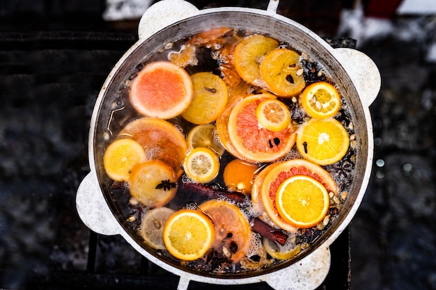 Mulled spicy vine with oranges in pot in street food market colorful hot alcohol drink at fair festi