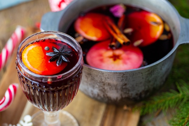 Mulled wine in a beautiful glass next to the saucepan. Hot drink in a glass. Christmas concept. Family evening with a hot drink.